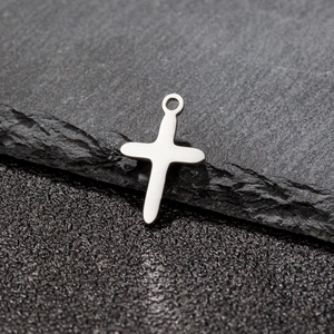 Detailed close-up of a minimalist silver stainless steel cross pendant on stone