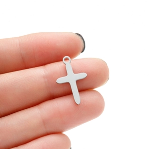 Detailed macro view of polished silver stainless steel cross pendant held by hand