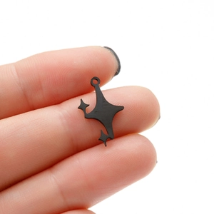 Vue macro montrant la taille d'un pendentif étoile asymétrique noir mat sur un doigt