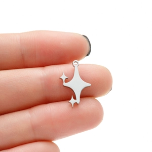 Détail macro d'un pendentif étoile en acier poli tenu par les doigts pour bijoux DIY