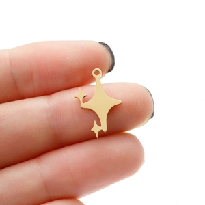 Détail d'un petit pendentif étoile en acier inoxydable doré tenu dans la main pour la taille