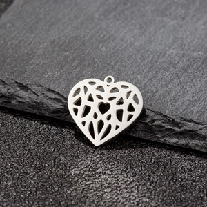 Close-up of heart-shaped hollow metal pendant with geometric mesh on dark stone