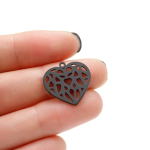 Detail of matte black heart pendant with geometric hollow design held between fingers