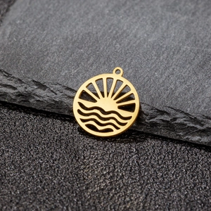 Macro shot of gold sun and wave pendant on black slate showing fine metal detail