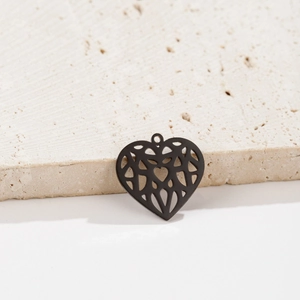 Detail of matte black hollow origami heart pendant on natural stone texture background