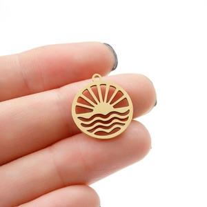 Close-up of golden circular hollow pendant with sun rays and sea waves pattern