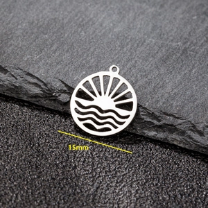 Macro shot of 15mm silver hollow wave and sun pendant on stone background