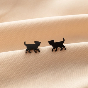Detailed macro view of matte black stainless steel cat earrings on beige silk fabric