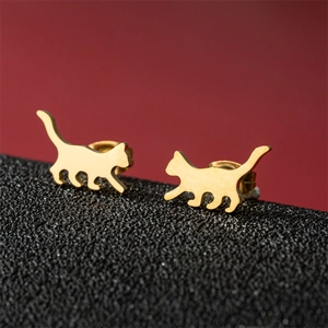 Macro shot of gold-plated walking cat silhouette earrings on a black display board