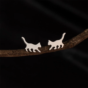 Minimalist silver cat silhouette stud earrings displayed on a natural tree branch