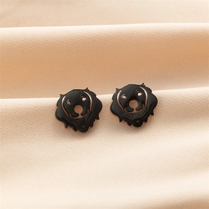 Macro shot of gold dog silhouette earrings with black enamel on a silk background