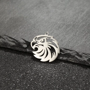 Close-up of stainless steel eagle pendant with intricate hollow-out details on rock texture