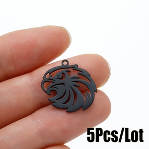 Detail view of 5 matte black eagle head charms held between fingers for size scale