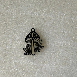 Detailansicht eines schwarzen Pilzanhängers mit Mond- und Sternengravuren für DIY-Schmuck