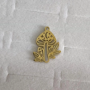 Detail eines goldenen Pilzanhängers mit Mond- und Sternenausschnitten für DIY-Schmuck