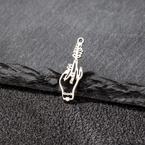 Detailed macro view of a silver gothic hand and leaf pendant on a dark stone surface