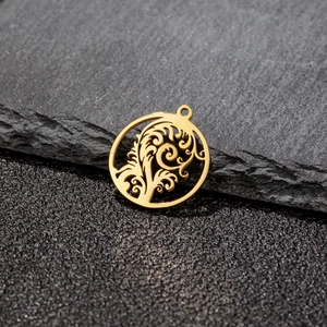 Macro view of a gold-toned circular cutout tropical tree leaf pendant on a stone base