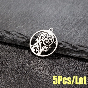 Macro shot of 5pcs set round cutout stainless steel tropical tree leaf pendants on stone