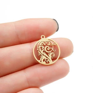 Golden round hollow tropical leaf pendant in stainless steel held by hand