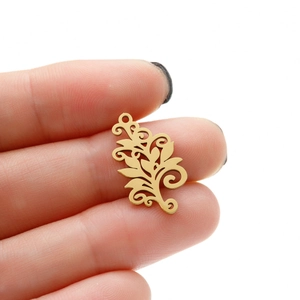 Detailed view of a gold bohemian tree of life pendant held by hand for scale