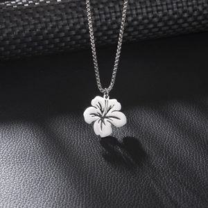 Minimalist stainless steel flower pendant necklace on a textured black leather surface