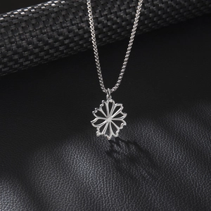 Minimalist silver-toned hollow flower pendant necklace on a premium black leather background