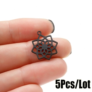 Close-up of five black stainless steel mandala flower pendants held in hand for scale