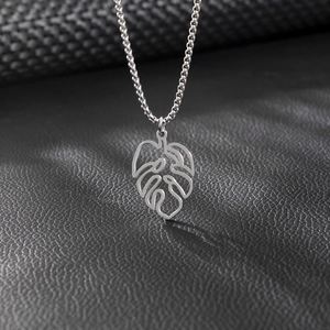 Close-up of a silver hollowed monstera leaf pendant on a delicate chain necklace
