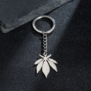 Polished stainless steel maple leaf pendant keychain on a minimalist dark stone background