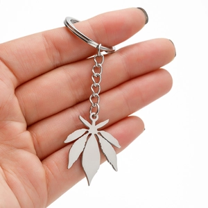 Detailed close-up of a polished stainless steel maple leaf pendant keychain held in hand