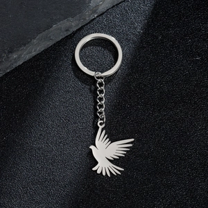 Polished stainless steel dove pendant keychain with metal chain on a textured background