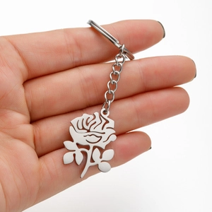 Close-up of a silver stainless steel rose flower pendant keychain held in hand