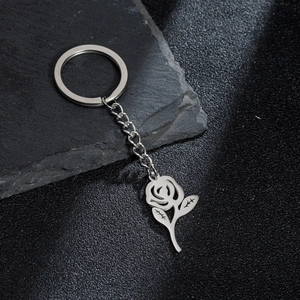 Minimalist stainless steel rose pendant keychain on dark stone texture background