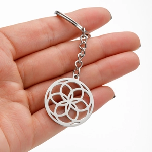 Hand holding silver stainless steel keychain with flower of life hollow pendant design