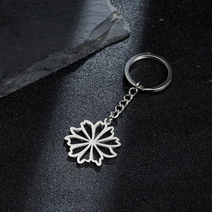 Silver stainless steel keychain with hollow daisy flower pendant on black textured surface