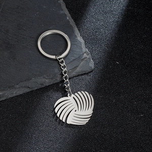 Polished stainless steel origami heart keychain pendant on a dark natural stone background