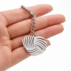 Minimalist stainless steel heart keychain held by hand featuring a hollow artistic texture