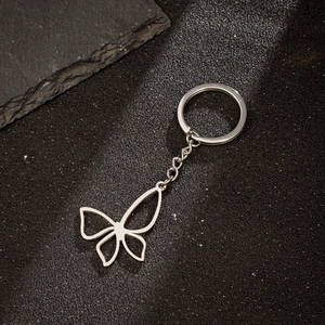 Detailed view of a silver hollow butterfly pendant keychain on a textured stone surface
