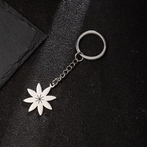 Polished stainless steel keychain with starburst leaf pendant on a black textured surface