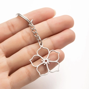 Close-up of a hollow cherry blossom keychain in polished stainless steel held by hand