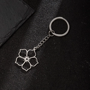 Macro shot of silver stainless steel daisy pendant keychain on a black textured surface