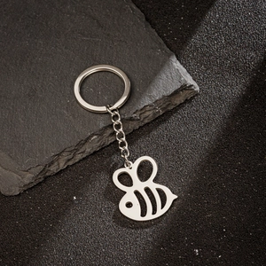 Polished stainless steel bee charm keychain on a textured dark background for accessories