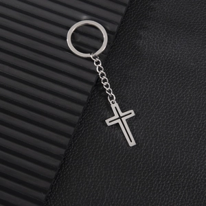 Modern hollow cross keychain in polished stainless steel on a textured black background