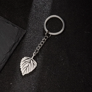 Polished stainless steel keychain with leaf pendant on a textured dark stone background