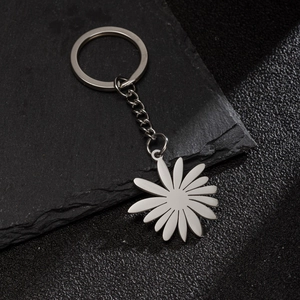 Minimalist stainless steel keychain with a delicate sunflower petal pendant on stone texture