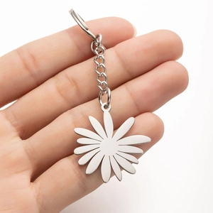 Minimalist stainless steel daisy flower pendant keychain held against white background