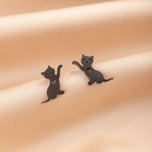 Boucles d'oreilles chat noir mat avec découpes cœur sur fond en satin champagne