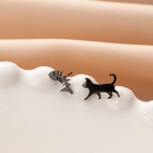 Detail view of asymmetric matte black stainless steel cat and fishbone stud earrings