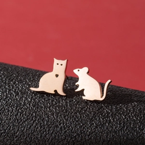 Detailed macro of asymmetric rose gold cat and mouse earrings on red and black texture