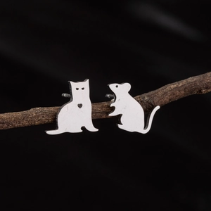 Asymmetric stainless steel Tom and Jerry stud earrings on a dark wooden branch